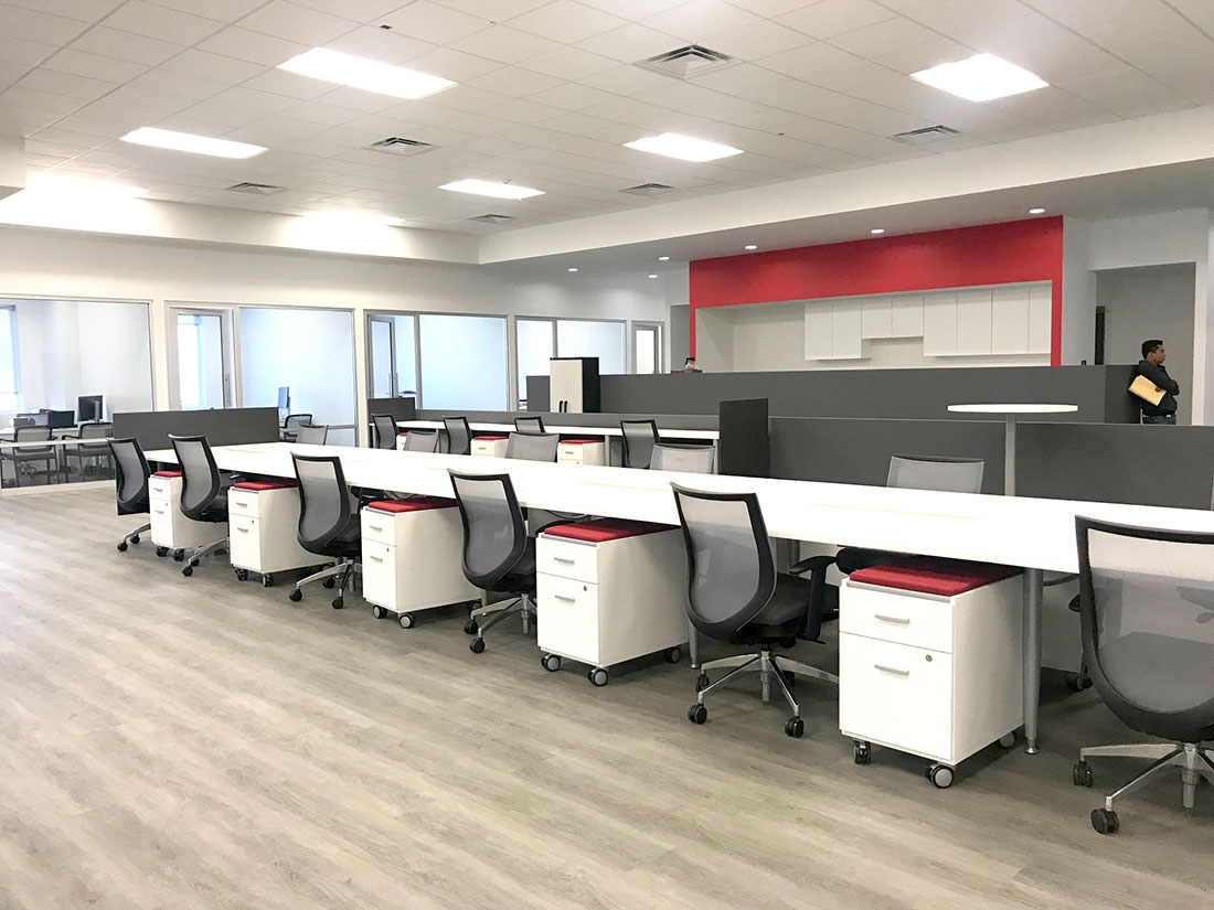 Bancada de trabajo blanca con cajoneras rodantes y sillas de malla en oficina de Tijuana