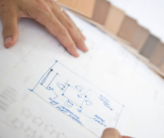 Arquitecto trazando un plano de distribución junto a muestras de acabados de madera
